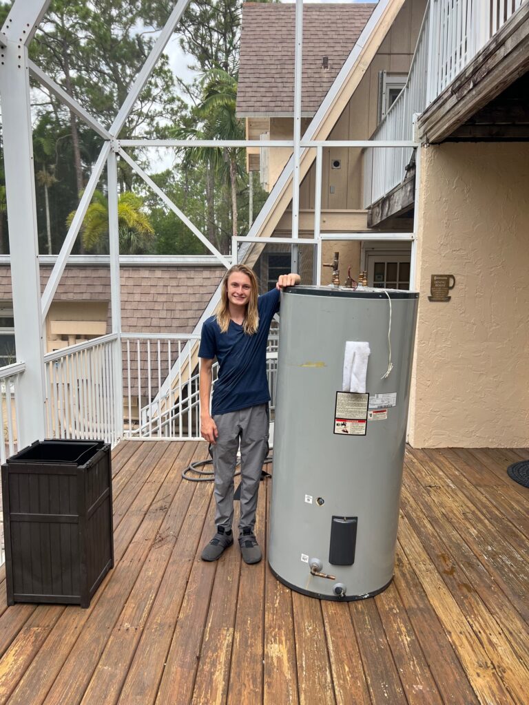 WHE team member beside a large water heater outdoors