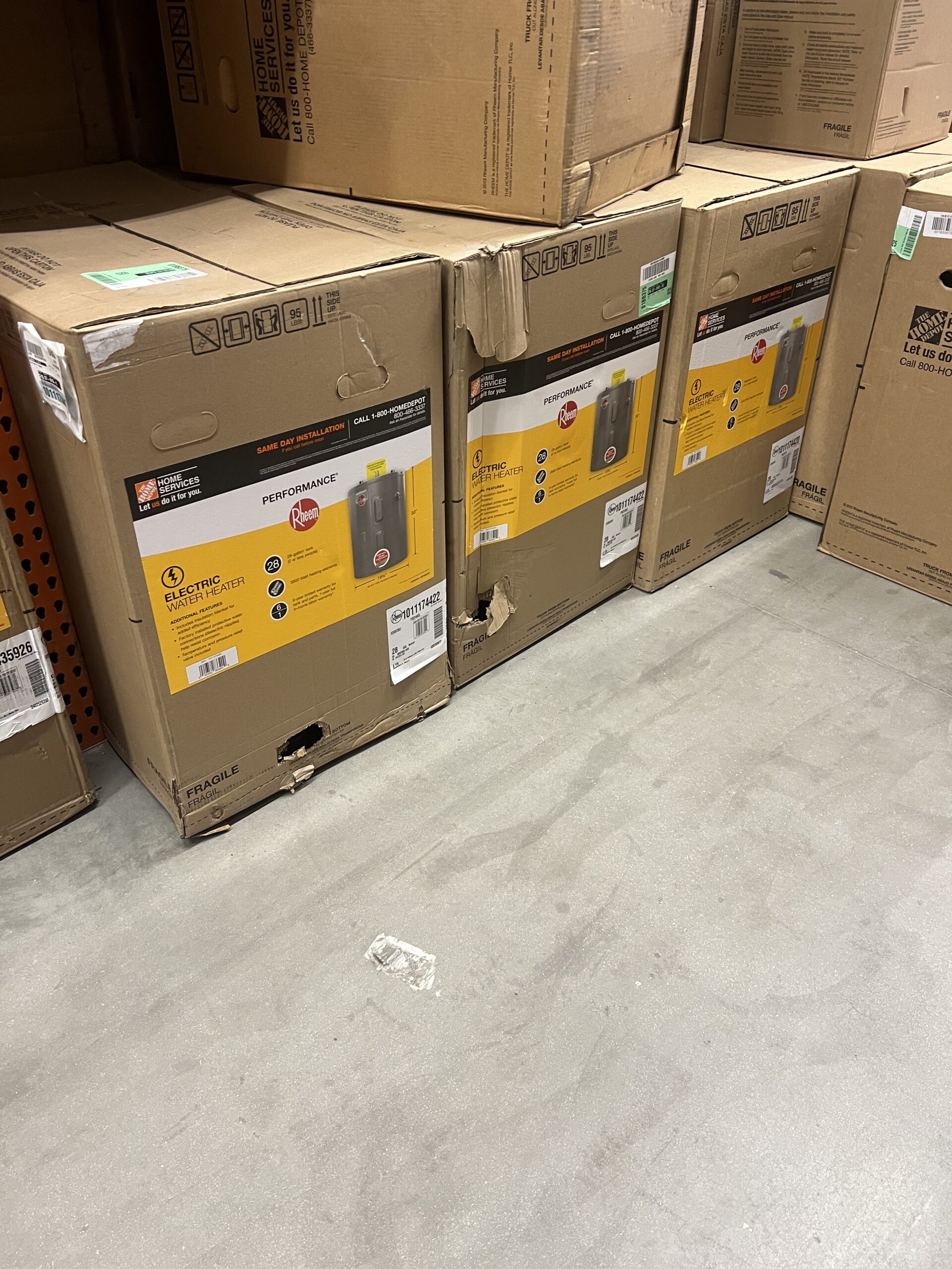 Rheem Performance electric water heaters in their retail cartons on a shelf at Home Depot