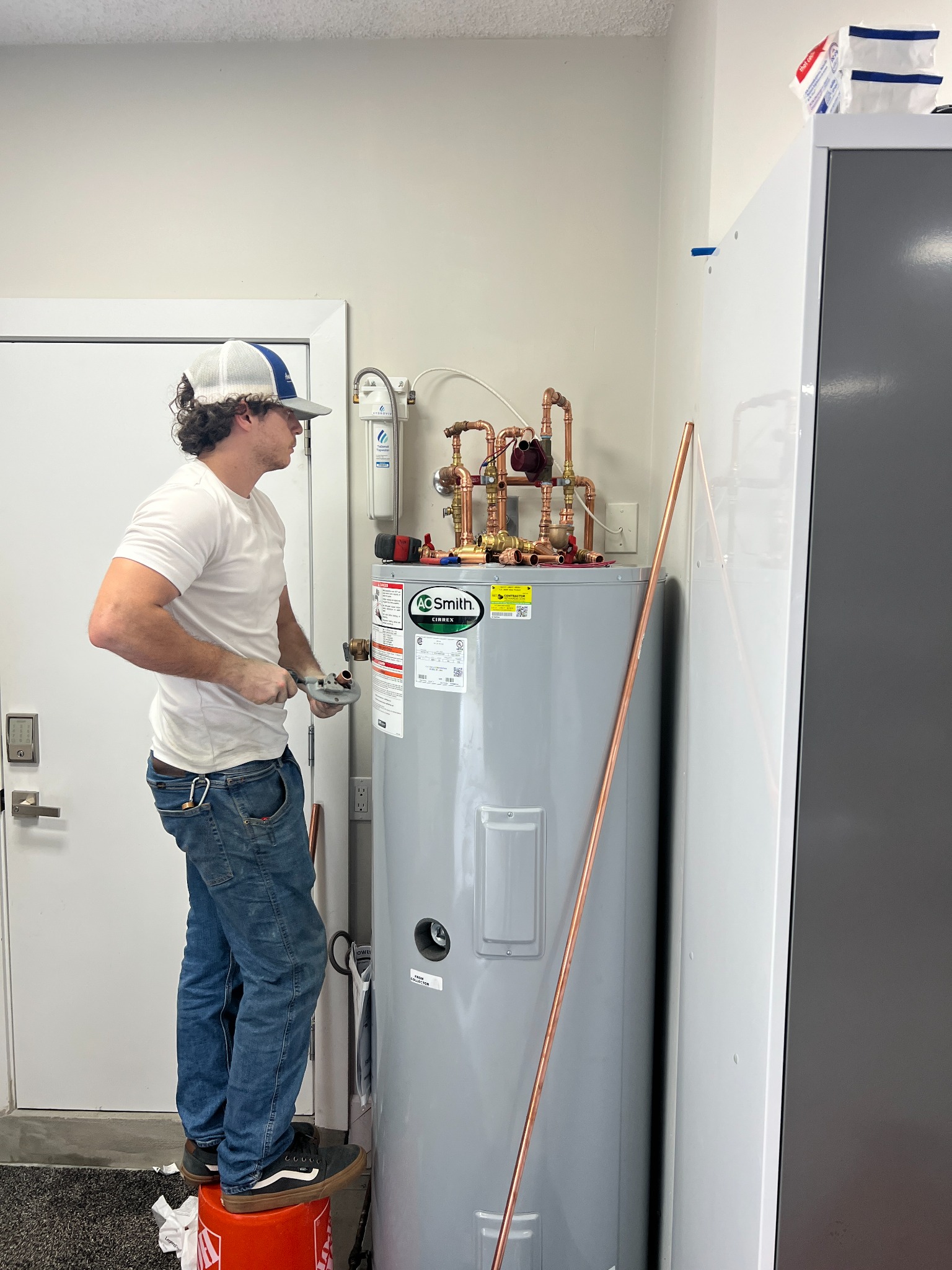 WHE plumber preparing copper pipe beside an A. O. Smith Cirrex solar water heater during installation.