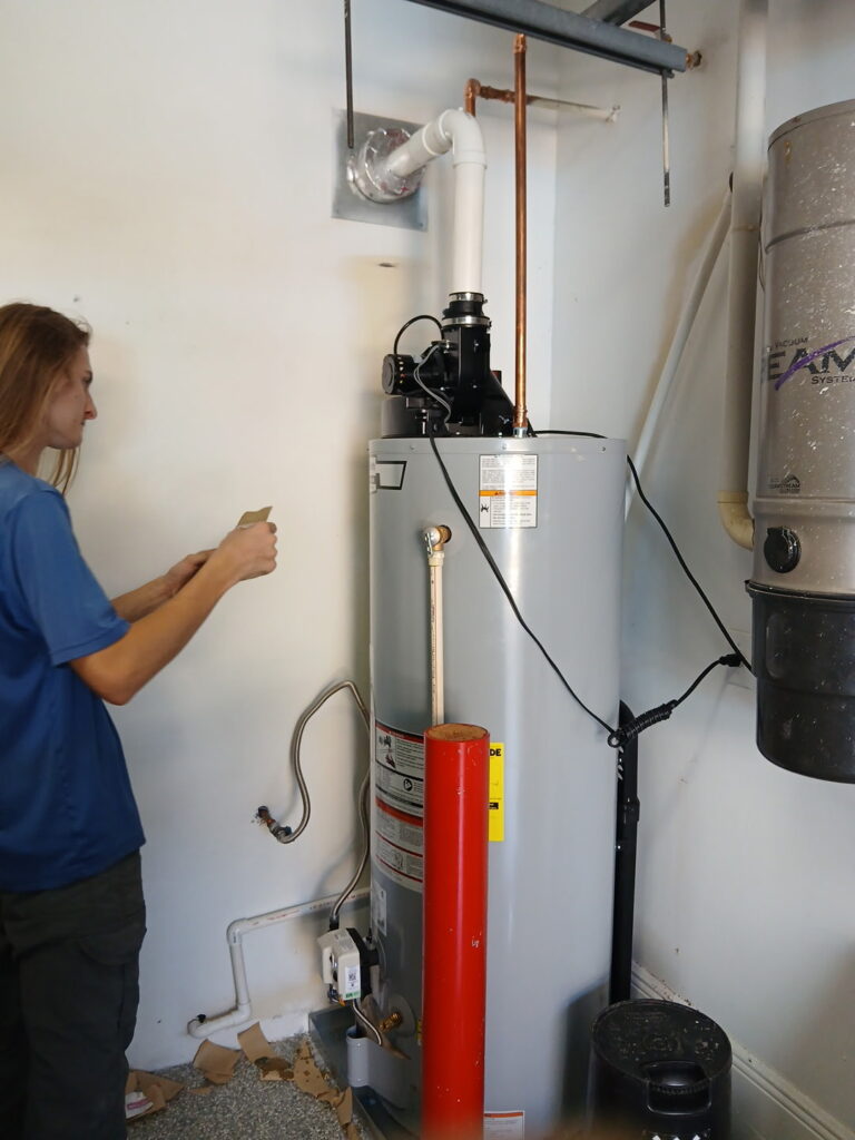 WHE team member beside a gas tank water heater during a power-vent installation
